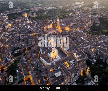 Blick aus der Vogelperspektive auf den beleuchteten Dom von Siena und die Piazza del Campo, mit warmen Lichtern, die Schatten auf die alten Dächer werfen, Siena, Toskana, Italien. Stockfoto