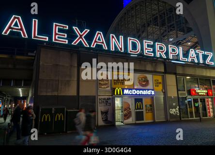 Nachtansicht auf das beleuchtete Schild „Alexanderplatz“ am Bahnhof und U-Bahn-Bahnhof in Berlin. Über dem Eingang leuchten ikonische Neonbuchstaben. Stockfoto