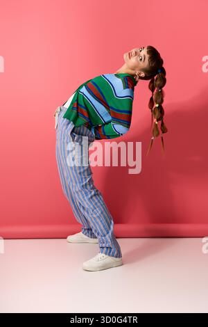 Die charmante junge Frau zeigt ihren einzigartigen Sinn für Mode mit verspielter Kleidung und einer lustigen Pose. Stockfoto