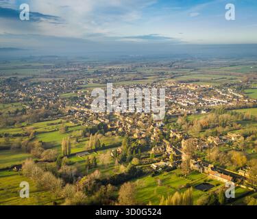 Blick aus der Vogelperspektive auf goldenes Sonnenlicht, das die sanften Hügel und die malerische Dorfarchitektur der Cotswolds betäubt und einen malerischen Wandteppich des ländlichen Englands schafft., Cotswolds, England, Großbritannien. Stockfoto