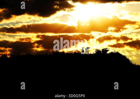 Silhouetten von Menschen auf einem Hügel mit Sonnenuntergang über Stockfoto