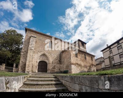 Historische Steinkirche mit Glockenturm unter hellem bewölktem Himmel in covarrubias, Spaindefault Stockfoto