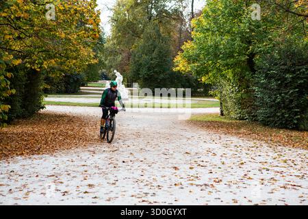 Radfahrer fahren während der Herbstsaison entlang des blattbedeckten Parkwegs und genießen die Outdoor-Bewegung und die Natur in der Umgebung. Stockfoto