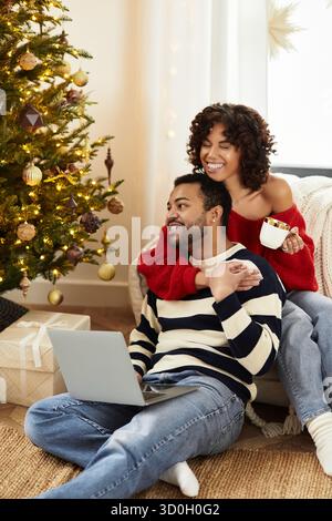 Glückliches Paar genießt Weihnachten zusammen am geschmückten Baum und teilt Lachen und Wärme. Stockfoto