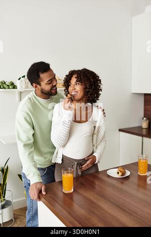 Ein Paar teilt einen verspielten Moment zu Hause, während sie ihre Schwangerschaft mit Liebe und Freude feiern. Stockfoto