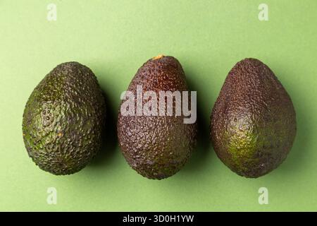 Overhead-Ansicht von drei Avocados auf grünem Hintergrund Stockfoto