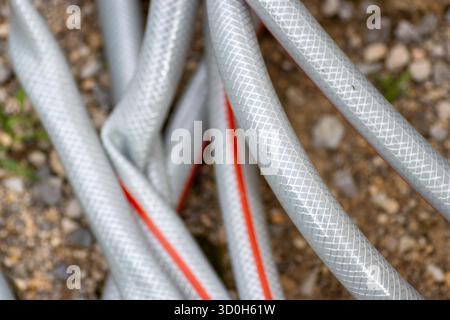 Grau und rot benutzte Schlauchleitungen, die auf dem Boden liegen Stockfoto