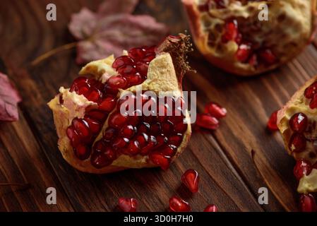 Granatapfel mit Herbstblättern auf dunklem hölzernem Hintergrund Stockfoto