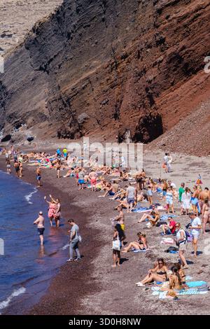 Santorin, GR - 4. September 2025: Viele Touristen genießen die Sonne am berühmten roten Strand von Santorin Stockfoto