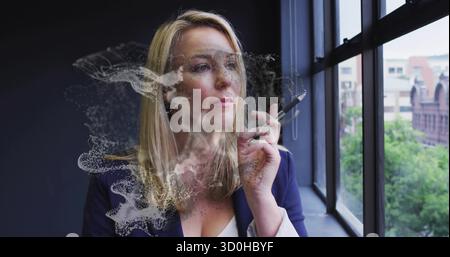 Schaut Frau mit Blazer, die Eingabestift an industriellem Fenster im Büro hält, Staubeffekt Stockfoto