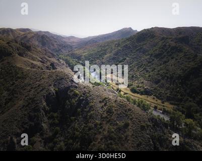 Aus der Vogelperspektive des sich windenden, reflektierenden Flusses, der durch die zerklüftete, strukturierte Landschaft der Berge, Samtskhe-Javakheti, Georgien, schneidet. Stockfoto