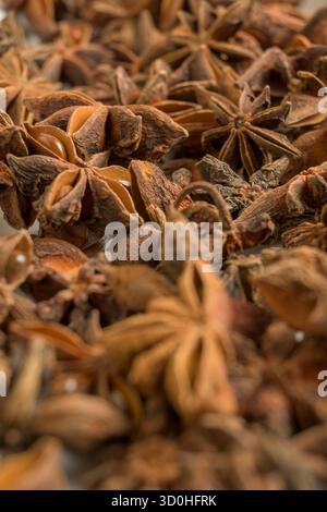 Detaillierte Nahaufnahme getrockneter Sternanisschoten mit natürlicher Textur und warmen Brauntönen, perfekt für kulinarische oder aromatische Gewürzthemen. Stockfoto