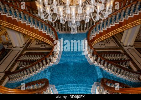 Riesige Palasttreppe mit blauem Teppich und Kronleuchter Stockfoto