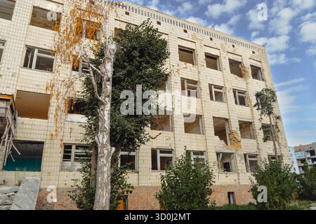 Tiefwinkelansicht eines mehrstöckigen Wohngebäudes, das durch den Krieg schwer beschädigt wurde, mit zahlreichen zerstörten Fenstern und freiliegenden Innenräumen Stockfoto