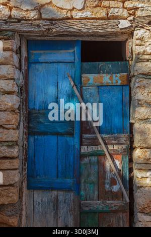 Blaue Tür und Steinmauer im Dorf Chora - Insel Folegandros, Kykladen, Griechenland Stockfoto