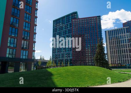 Zeitgenössischer städtischer Wohnkomplex mit farbenfrohen Hochhäusern vor einem klaren blauen Himmel Stockfoto