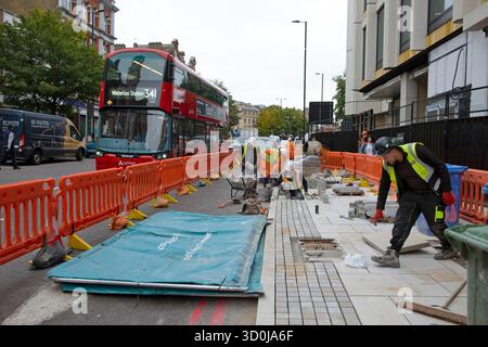 Straßenpflasterreparatur Instandhaltungsarbeiter Arbeiter arbeiten Verlegen von Gehsteig Pflasterplatten 341 Bus zur Waterloo Station London England Großbritannien Großbritannien Großbritannien Großbritannien Stockfoto