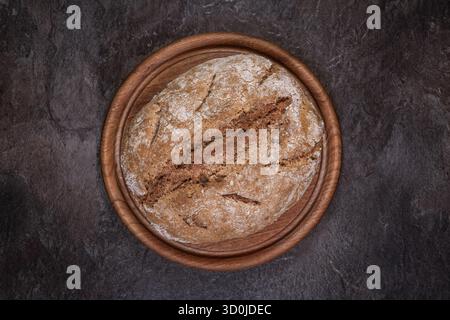 Vollkornbrot aus Sauerteig mit Walnüssen auf rundem Holzbrett, Ansicht von oben nach unten mit Kruste, zentrierte Zusammensetzung. Stockfoto