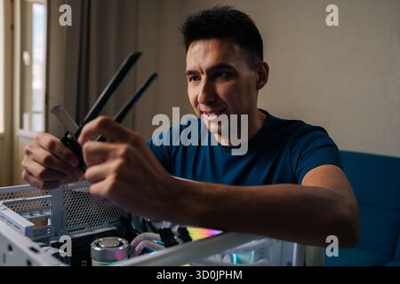 Positiver Computertechniker, der ein drahtloses Netzwerkmodul in einen benutzerdefinierten Desktop-Computer einfügt, verbessert die Systemkonnektivität für Zuverlässigkeit Stockfoto