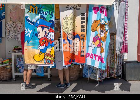 Touristen in einem Souvenirshop, Strandtücher mit verschiedenen Comic-Motiven, in der Stadt Vila Real de Santo António, an der Grenze zu Spanien, Algarve, Por Stockfoto