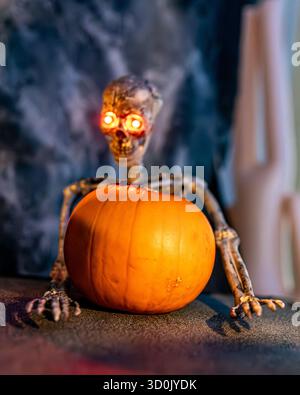 Bild eines menschlichen Skeletts neben einem leuchtenden Kürbis, was eine gruselige und geheimnisvolle Halloween-Atmosphäre schafft. Die Komposition kombiniert klassisch Stockfoto