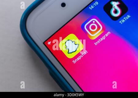 Nahaufnahme eines Smartphone-Bildschirms mit Snapchat-, Instagram- und TikTok-Apps, die moderne digitale Kommunikation und soziale Trends symbolisieren. Stockfoto