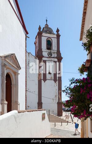 Touristen gehen vorbei am Glockenturm der Kathedrale Sé, einem gotischen Wahrzeichen in der mittelalterlichen Stadt Silves, an der Algarve. Stockfoto