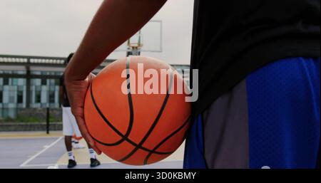 Basketballspieler in Sportbekleidung hält Ball auf dem Platz im Freien, mit Basketball und Kopierraum Stockfoto