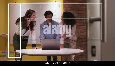 Besprechen Sie drei Kollegen, die sich mit Whiteboard-Markern über einen Laptop im Konferenzraum lehnen Stockfoto