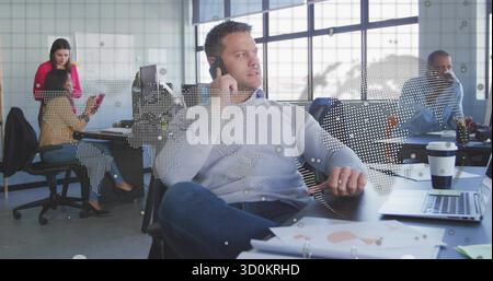 Antwort auf Mann mittleren Alters, der im Großraumbüro auf einem Smartphone mit Monitoren, Laptop und Weltkarte spricht Stockfoto