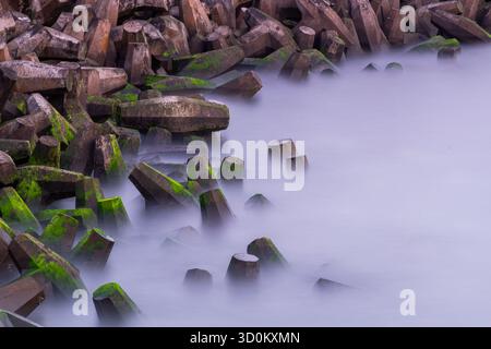 Langzeitbelichtung von Betonmeerabwehrungen bei Torness mit Grünalgen Stockfoto