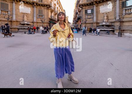 Frau, die einen Spaziergang durch den Quattro Canti-Platz in Palermo, Sizilien, genießt und ein sizilianisches Cannolo hält. Eine Mischung aus Geschichte, Reisen und langsam lebendigem Charme Stockfoto