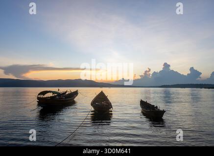 Goldener Sonnenuntergang über einem ruhigen Hinterwasser mit angelegten Fischerbooten Stockfoto