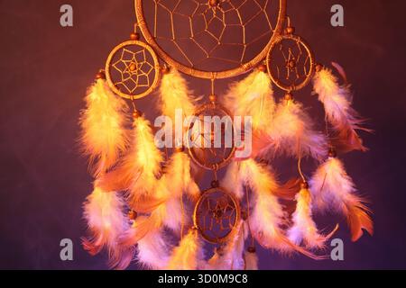 Schöner Traumfänger und Rauch in Farbe Licht auf dunklem Hintergrund, Nahaufnahme Stockfoto