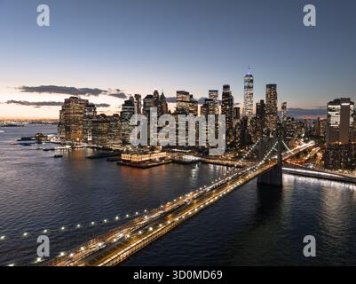 Aus der Vogelperspektive der Brooklyn Bridge, die sich über den East River in Richtung der beleuchteten Skyline von Lower Manhattan, New York, New York, USA erstreckt. Stockfoto