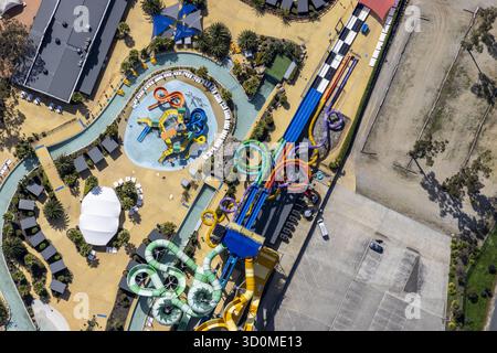Aus der Vogelperspektive auf den pulsierenden Wasserspielplatz mit verwinkelten Rutschen und faulen Flüssen im Kontrast zur trockenen Landschaft, Tynong North, Victoria, Australien. Stockfoto