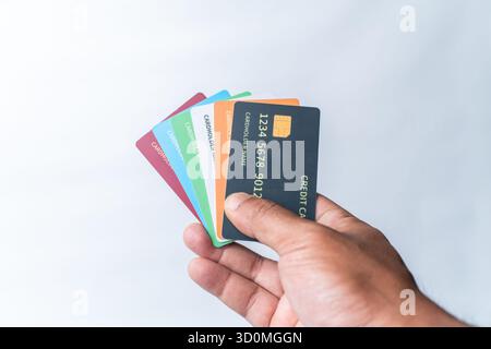 Nahaufnahme eines Mannes Hand, der einen Fan mehrerer bunter Kreditkarten vor einem sauberen weißen Hintergrund hält. Stellt mehrere Zahlungen dar Stockfoto