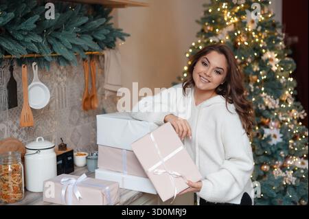 Frau, die Geschenke in der festlichen Weihnachtsküche hält Stockfoto
