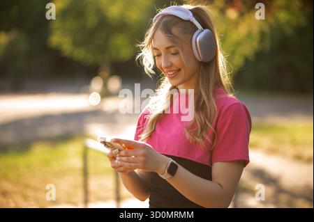 Frau mit Kopfhörern, die ihr Smartphone im Freien nutzt Stockfoto