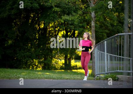 Frau, die im Park joggt, trägt rosa Sportbekleidung Stockfoto