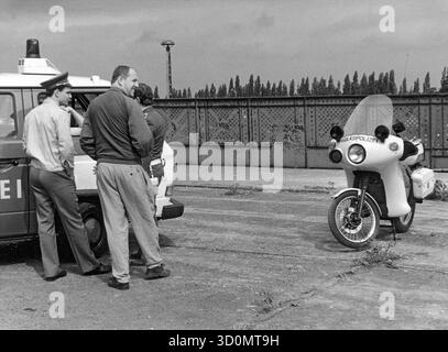 DEU, Deutschland, Berlin, 18.03.1990: West- und Ost-Berliner Polizeibeamte treffen sich auf der Behmstrassenbrücke an der Grenze zwischen dem westlichen Stadtteil Wedding und dem östlichen Stadtteil Prenzlauer Berg. Rechts befindet sich ein Volkspolizeimotorrad, rechts ein West-Berliner Polizeibus, davor ein Mitglied der DDR-Grenztruppen, ein Zivilpolizist und der Volkspolizei-Motorradpolizist. [Automatisierte Übersetzung] Stockfoto