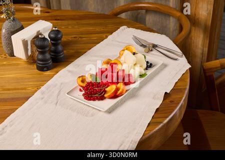 Ein entzückender Obstteller, künstlerisch auf einem rustikalen Holztisch ausgestellt Stockfoto