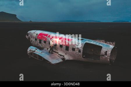 Luftaufnahme der Skelettreste der DC-3-Ebene auf dem schwarzen Sand von Sólheimasandur unter einem brütenden Himmel, Mýrdalshreppur, Island. Stockfoto