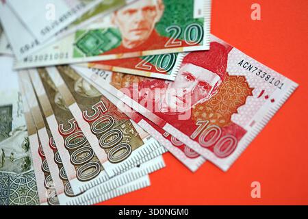 Pakistanische Rupien Banknoten auf rotem Hintergrund. Die aktuellen pakistanischen Geldrechnungen liegen in großer Höhe auf dem Tisch. Das Konzept des Geschäfts und der Investitionen in Pakistan Stockfoto