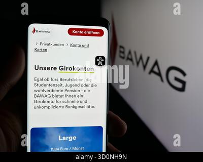 Stuttgart, Deutschland - 18.10.2025: Person mit Handy mit Webseite des österreichischen Finanzdienstleistungsunternehmens BAWAG auf dem Bildschirm vor dem Logo. Fokus Stockfoto