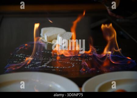 Hände des Küchenchefs mit Spachtel über Teppanyaki. Kochen von Gemüse, Fleisch und Meeresfrüchten auf heißem Hibachi-Grilltisch. Traditionelles Japanisch. Teppan Show. Cuisine People of World Konzept Stockfoto