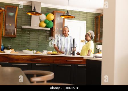 Seniorenpaar, das zusammen in der modernen Küche Essen zubereitet und Gespräche genießt. Kochen, Küchenutensilien, Lifestyle, Beziehung, kulinarisches, Zusammengehörigkeit || Model veröffentlicht Stockfoto