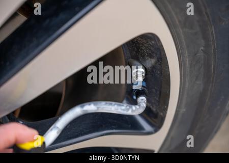 Selektiver Fokus auf chemisches Additiv, das aus einer Dose in einen Reifen gespritzt wird, um eine Panne zu reparieren Stockfoto