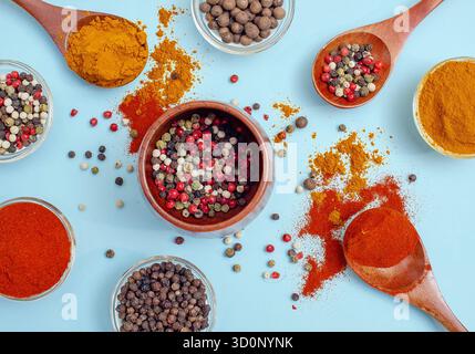 Aromatische Gewürze und Gewürze. Helle Farben indischer Gewürze. Farbige Paprika in der Schüssel auf hellblauem Hintergrund. Konsistenz von Würzmitteln Nahaufnahme. Stockfoto