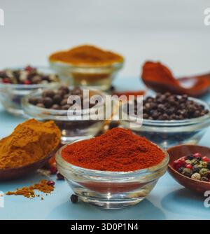 Aromatische Gewürze und Gewürze. Helle Farben indischer Gewürze. Orange Paprika in der Schüssel auf hellblauem Hintergrund. Konsistenz von Würzmitteln Nahaufnahme. Stockfoto